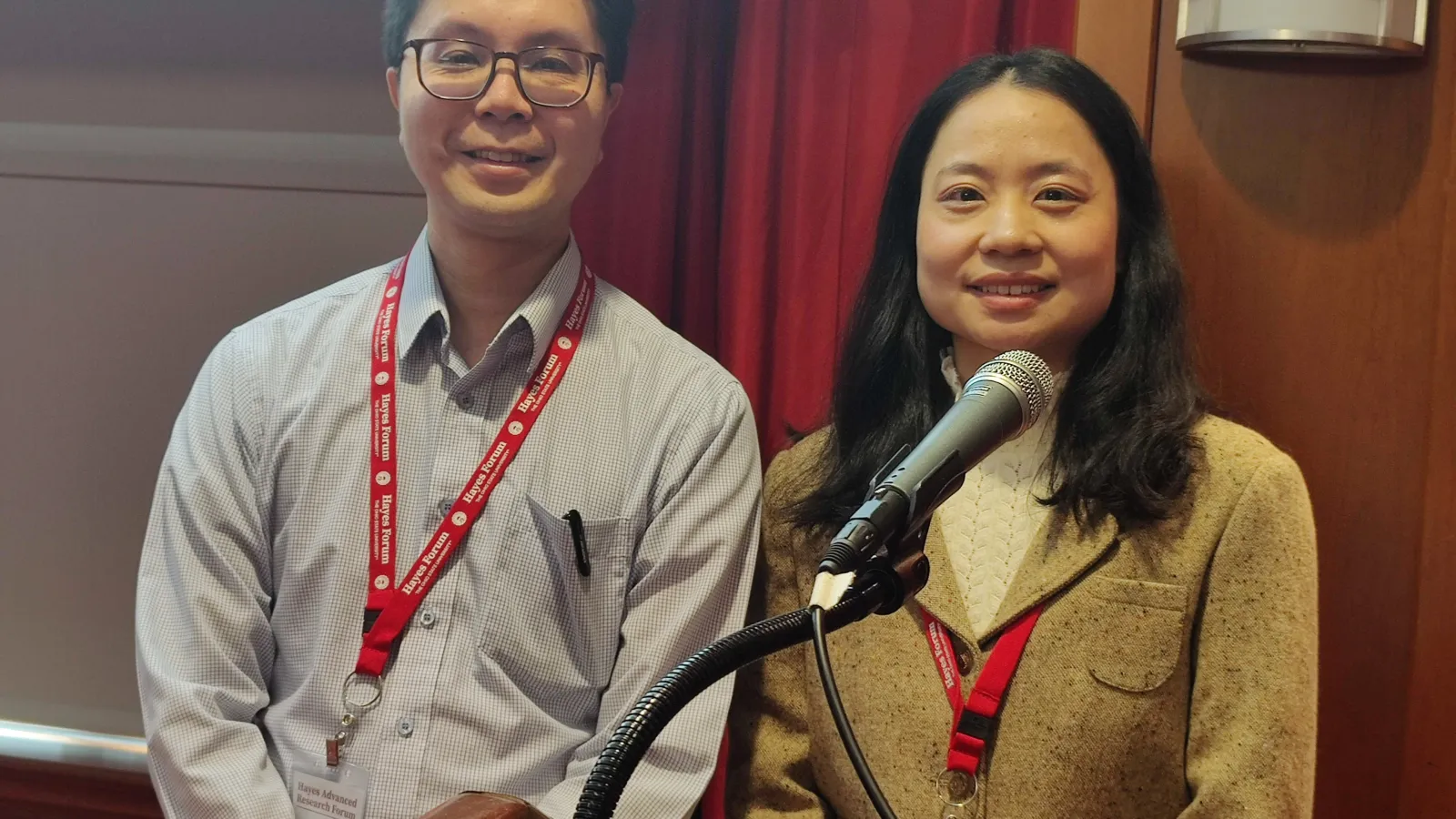 A man and woman are positioned in front of a podium, likely preparing to speak or present to an audience