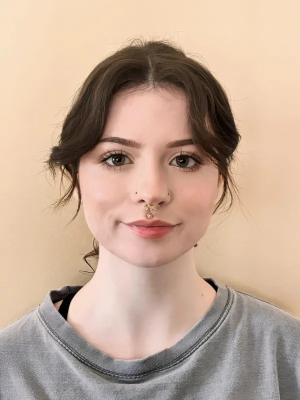 Smiling dark-haired woman wearing a gray shirt and nose ring