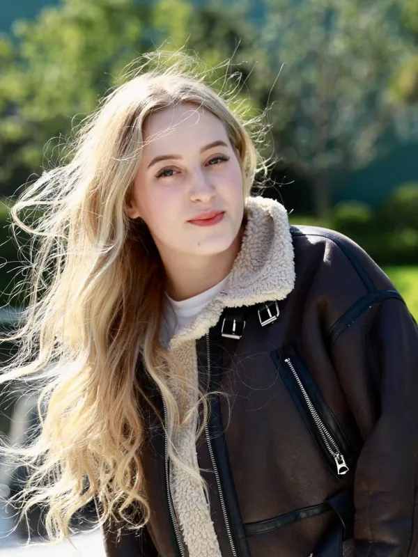 woman with light hair wearing a dark coat in an outdoor setting