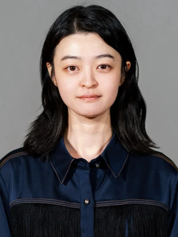 Woman with long dark hair and a navy blue blouse smiling